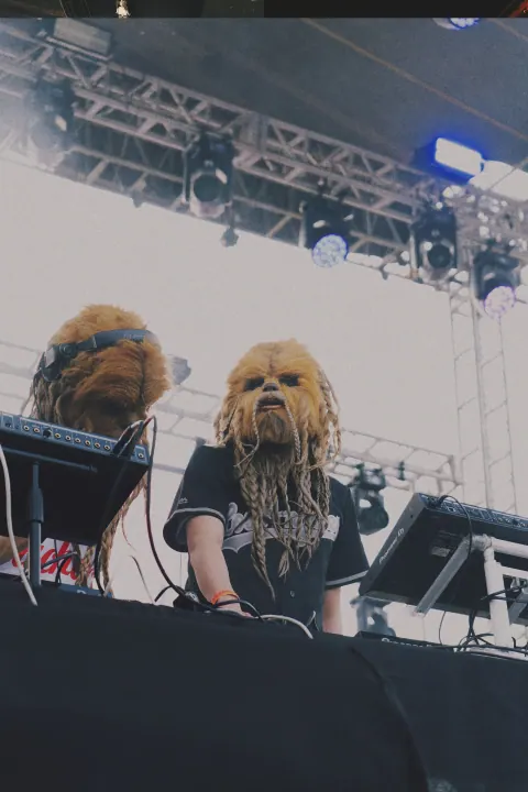 Artistas con máscaras detrás de la mesa de mezcla del festival.