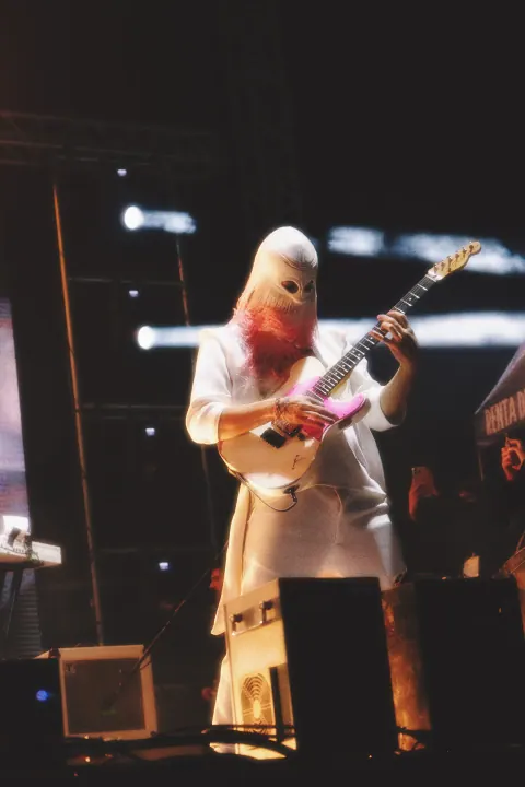 Guitarrista con vestimenta clara durante una presentación de Dängo.