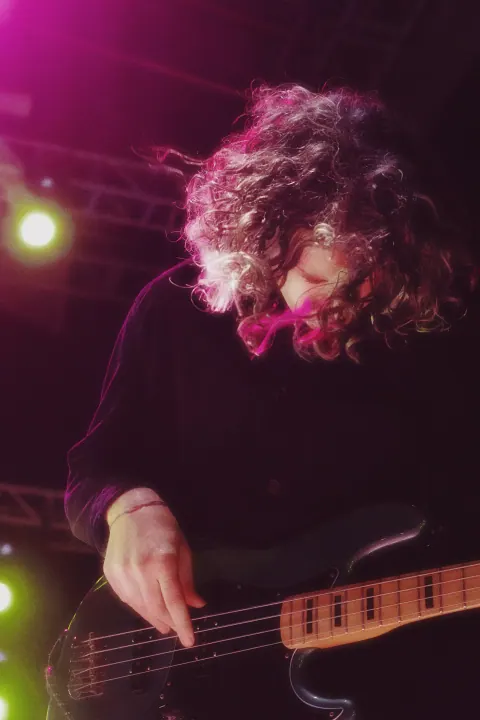 Bajista tocando bajo las luces rosas del escenario de Dängo.